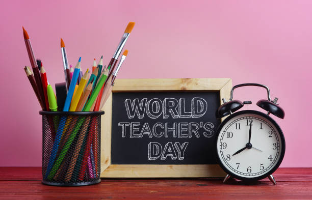 World Teacher's Day Text. Blackboard, Alarm Clock and School Stationary in Basket on Wooden Table Pink Background World Teacher's Day Text. Blackboard, Alarm Clock and School Stationary in Basket on Wooden Table Pink Background World Teachers Day stock pictures, royalty-free photos & images