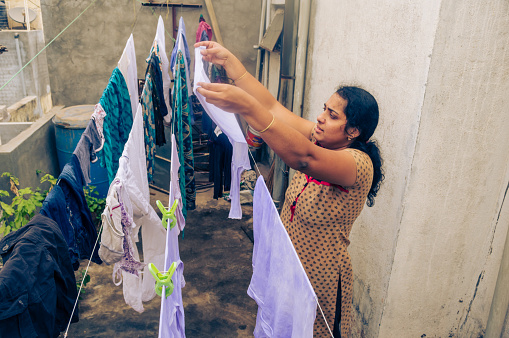 Indian woman drying clothes at home backyard