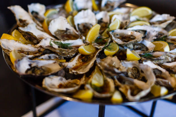 istock Oysters with lemon fruit on a black plate on a white wood table 1017024724