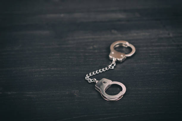 istock Handcuffs on a black wooden background. 1017035366