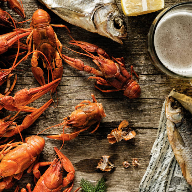 istock Fresh boiled crawfish and dried fish with a beer on a wooden table. 1017068004