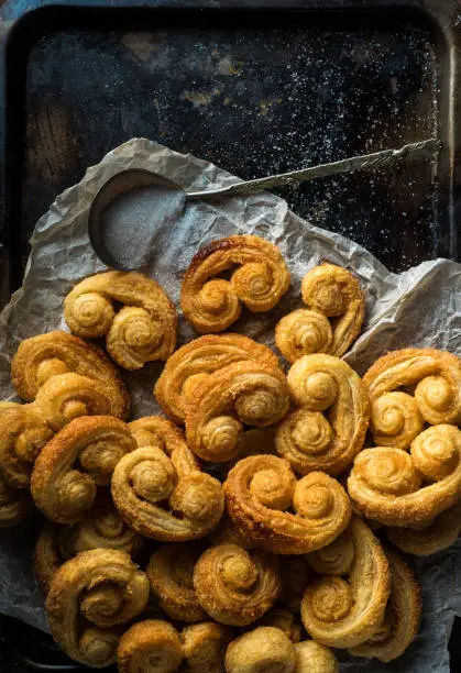 Photo of Delicious puff pastry ears cookies on a baking tray.