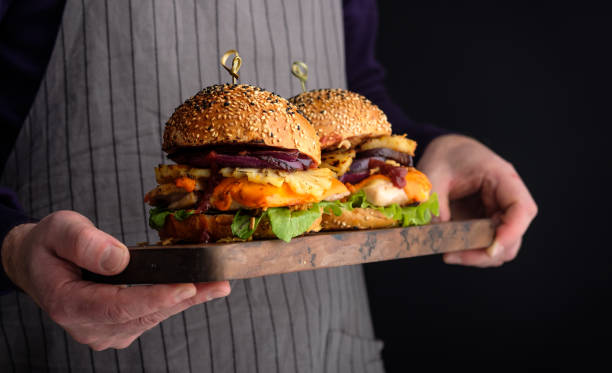 istock Chicken burger with pineapple. Men's hands hold a tray with a cheeseburger 1017068554