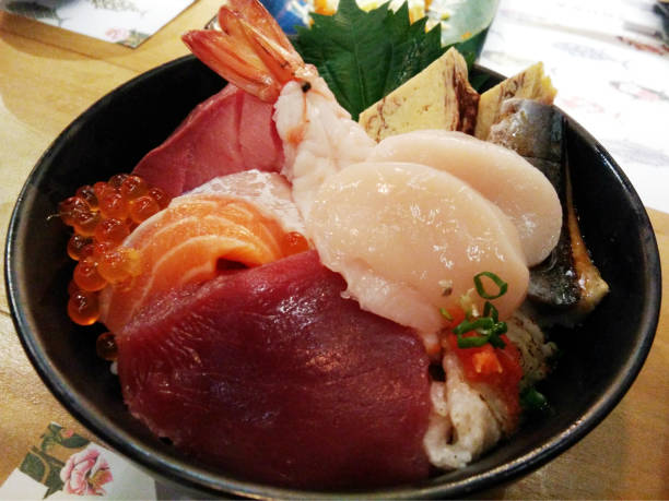 istock Chopsticks with Salmon sashimi with Mixed sliced fish sashimi on ice in black bowl. Sashimi Salmon Tuna Hamachi Prawn and Surf Calm set, raw fish, japanese food 1017070668