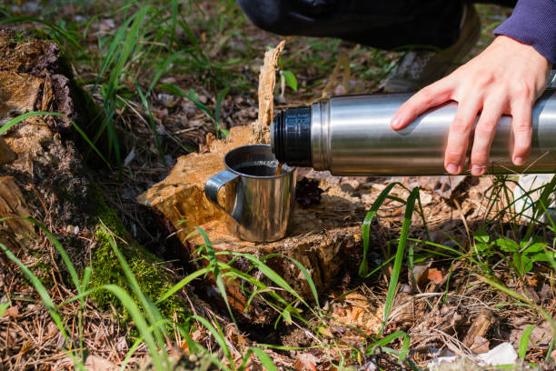 istock hiker pours tea from a thermos in a summer forest 1017083002