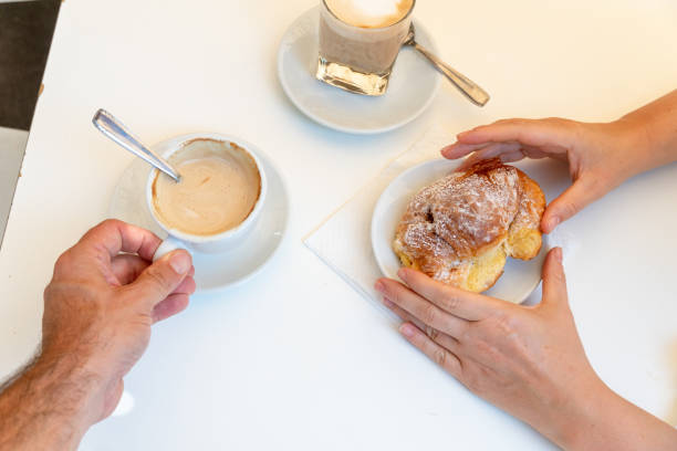 istock Two people's hands at breakfast table with cappuccino and croissant 1017083952