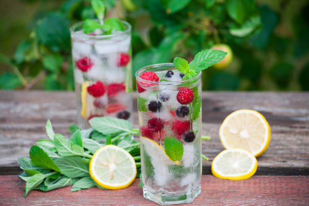 istock Cold lemonade with lemon, mint and berries in a transparent glass with facets. 1017097524