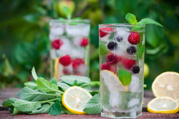 istock Cold lemonade with lemon, mint and berries in a transparent glass with facets. 1017097554