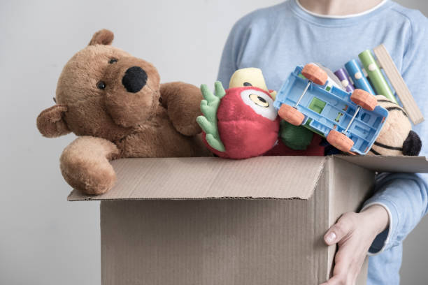 Male volunteer holding donation box with old toys stock photo