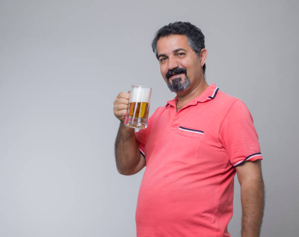 prise de vue studio d’un homme en surpoids avec un verre de bière - pot belly greed overweight excess photos et images de collection