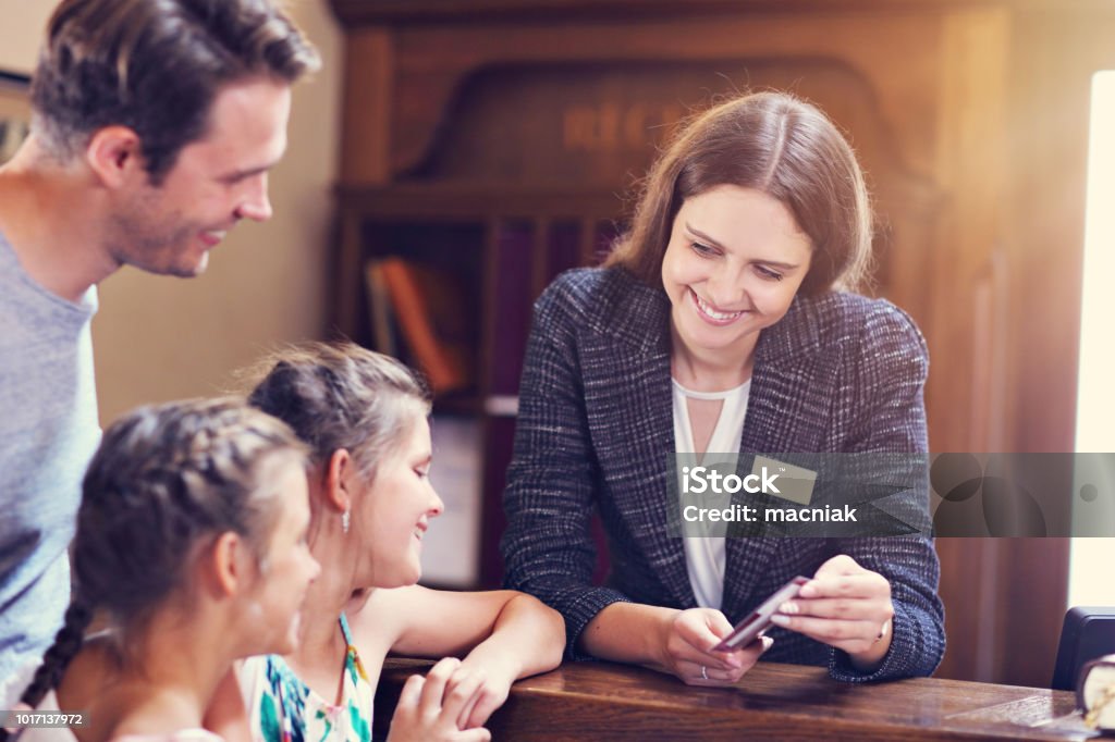 Happy family checking in hotel at reception desk Picture of family checking in hotel Hotel Stock Photo