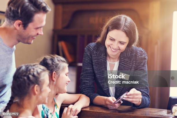 Happy Family Checking In Hotel At Reception Desk Stock Photo - Download Image Now - Hotel, Guest, Family