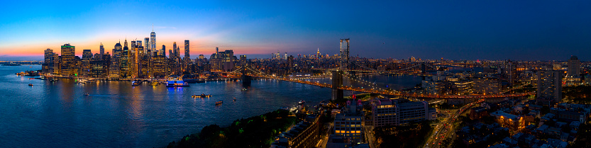 The aerial scenic panoramic view to illuminated Manhattan Downtown from Brooklyn Heights over the East River at the sunset. The clean hot summer evening, twilight time.