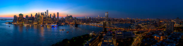 The aerial scenic panoramic view to Manhattan Downtown from Brooklyn Heights over the East River at the sunset. The aerial scenic panoramic view to illuminated Manhattan Downtown from Brooklyn Heights over the East River at the sunset. The clean hot summer evening, twilight time. brooklyn bridge photos stock pictures, royalty-free photos & images