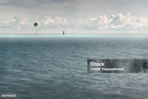 A Man Walks In Shallow Turquoise Water Near A Small Uninhabited Island Stock Photo - Download Image Now