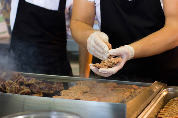istock Man fries meat and burger cutlets on a steaming grill 1017146914