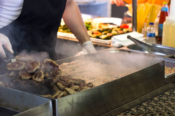 istock Man fries meat and burger cutlets on a steaming grill 1017147080