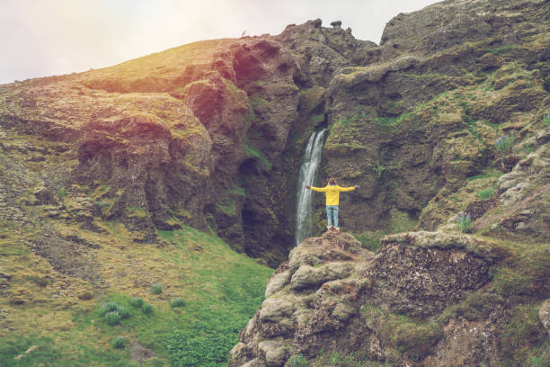 istock Young woman arms outstretched at spectacular waterfall 1017150042