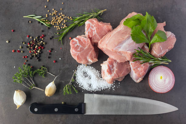viande crue fraîche avec des herbes, épices et un couteau de boucher se trouve sur la surface d’une pierre sombre. - veal rosemary meat steak photos et images de collection
