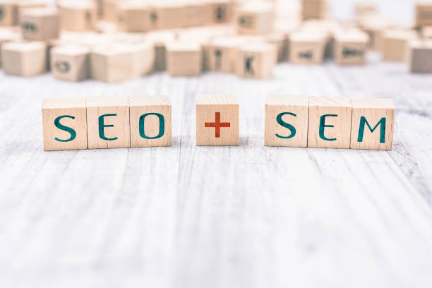 The Words SEO And SEM Formed By Wooden Blocks On A White Table stock photo