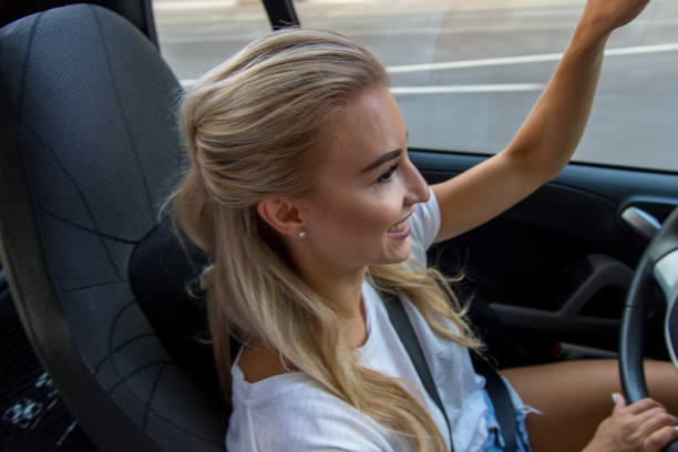 Blonde woman drives car A young blonde with a great, sporty figure drives a small car. sonnenbrille stock pictures, royalty-free photos & images