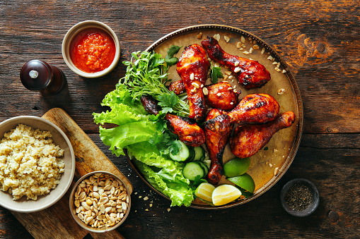 Barbecue chicken legs with barbecue sauce, vegetables, nuts and quinoa
