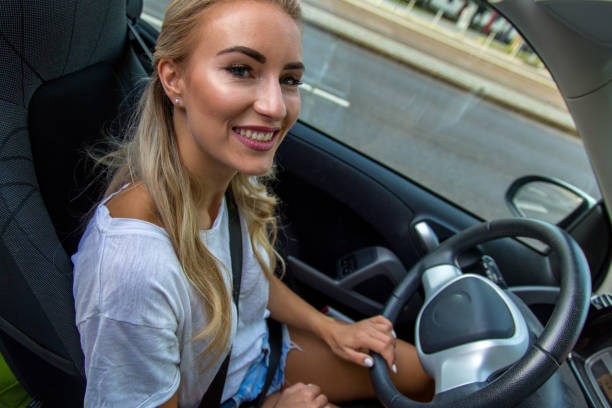 Blonde woman drives car A young blonde with a great, sporty figure drives a small car. sonnenbrille stock pictures, royalty-free photos & images