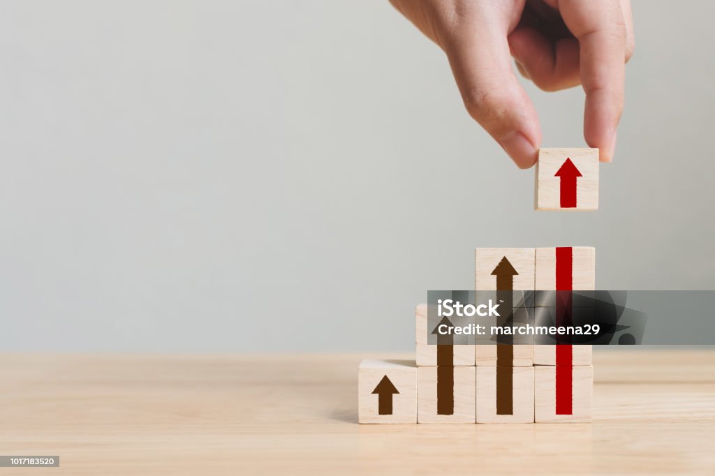 Hand arranging wood block stacking as step stair with arrow up. Ladder career path concept for business growth success process Growth Stock Photo