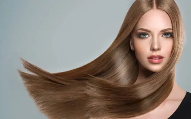 Young, brown haired woman  with straight and voluminous hair. Beautiful model with long, dense straight hairstyle and vivid make-up. Perfect flying hair and sexy look.Incredibly dense and shiny hair.