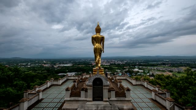 Time-lapse of Golden big buddha statue standing on hill with city at Wat Phra That Kao noi, Nan, Thailand