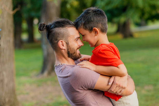 Being a father is the best title in world Photo of Happy Father and Son, face to face having fun outdoors. Laughing Dad with Little Boy enjoying nature together. Joyful Family. Free,freedom concept. Summer Holidays, vacation. Family, childhood and fatherhood concept - happy father and little son playing and having fun outdoors world title stock pictures, royalty-free photos & images