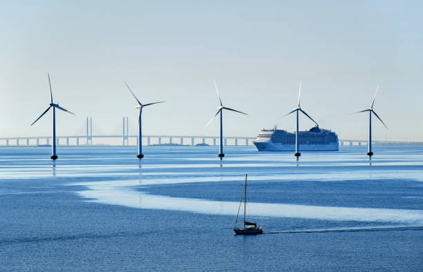 Large passenger ship and a small sailboat pass offshore wind turbines near the Oresund Bridge between Denmark and Sweden Copenhagen, Denmark - July 15, 2017: A very large passenger ship and a small sailboat pass offshore wind turbines near the Oresund Bridge between Denmark and Sweden. oresund region stock pictures, royalty-free photos & images