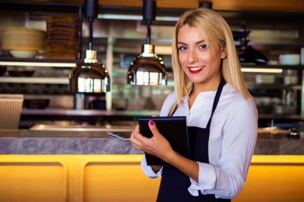 istock Business owner at her coffee shop looking at camera smiling while taking notes on a notepad 1017287542