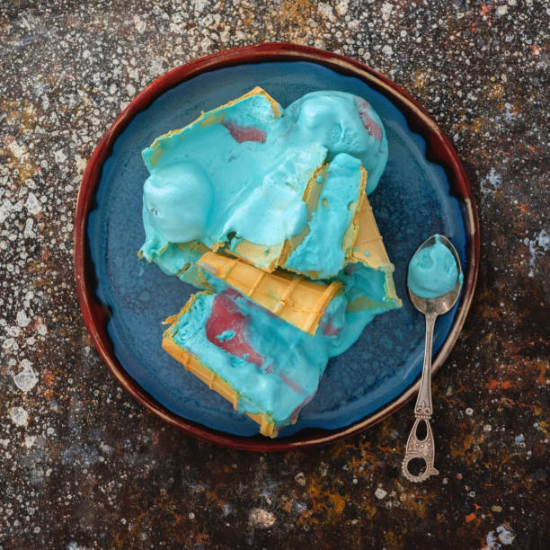 Blue ice cream in waffle cup melted on a plate.