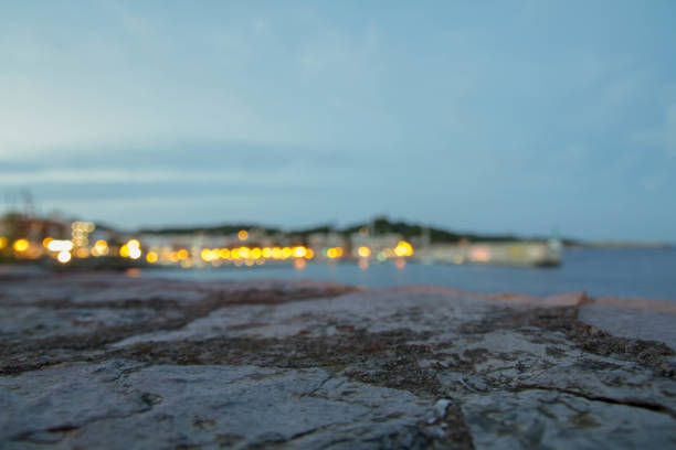 Rocky landscape at the front\nSea and city pier lights at the back