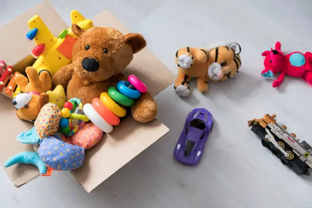 Photo of box of toys on the floor. Teddy bear in box,vintage tone. charitable contribution. donation. beneficence