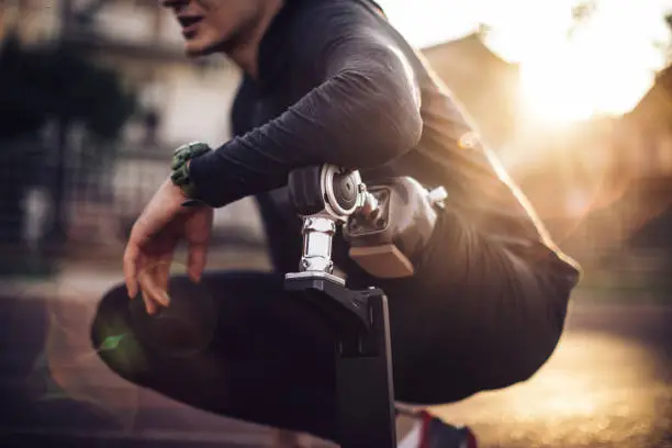 One man, sportsman with amputee leg and artificial limb, preparing for a run on the street in sunset.