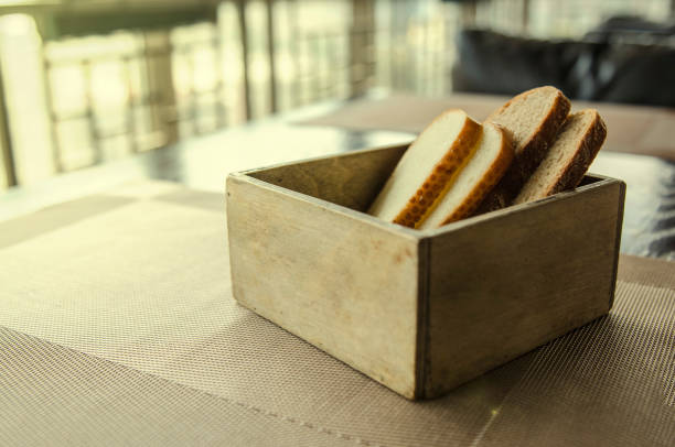Cut bread in wooden bread box. Four pieces of bread in a beautiful breadbox on a table in a cafe. Fresh cut bread in wooden bread box with background