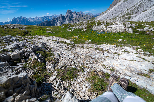 Close-up of woman's legs, view of the mountains around Tre Cime di Lavaredo (Three Pinnacles / Drei Zinnen), in Dolomite Alps, South Tyrol, Italy. Nikon D850.