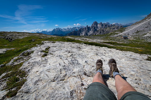 Close-up of woman's legs, view of the mountains around Tre Cime di Lavaredo (Three Pinnacles / Drei Zinnen), in Dolomite Alps, South Tyrol, Italy. Nikon D850.