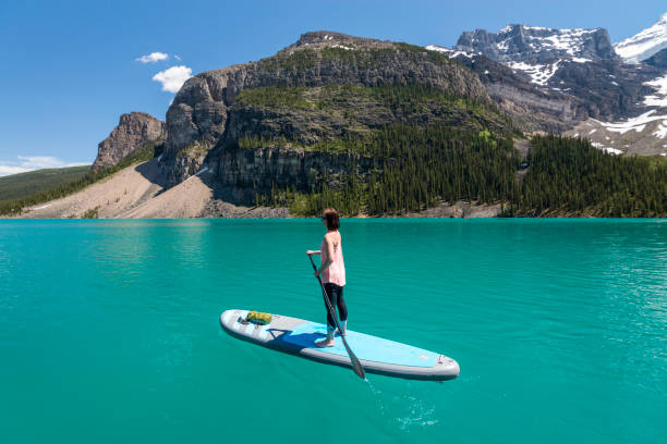 istock Woman plys stand up paddleboard (SUP), mountain lake 1017370340