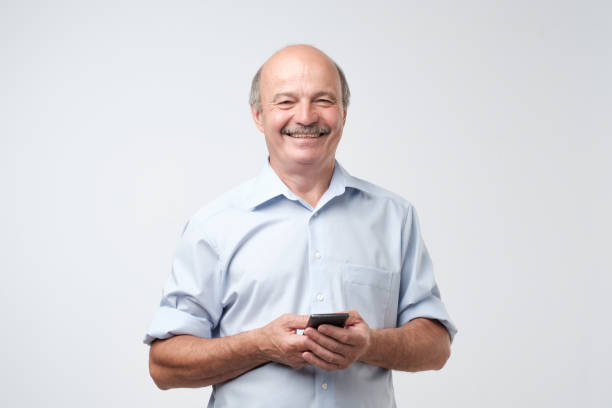 istock Typing text message. Smiling senior man with mustache standing on white isolated background 1017380288