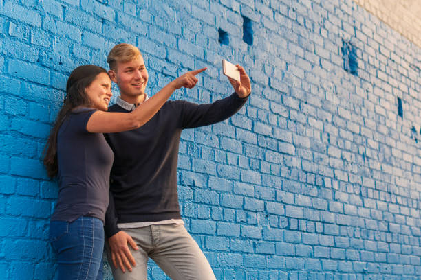 istock A mixed-race couple taking a selfie against a blue brick wall 1017431090