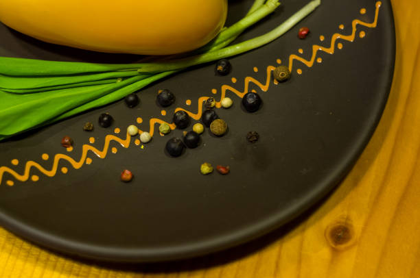 large yellow bell pepper and fresh green onions on a ceramic plate close-up