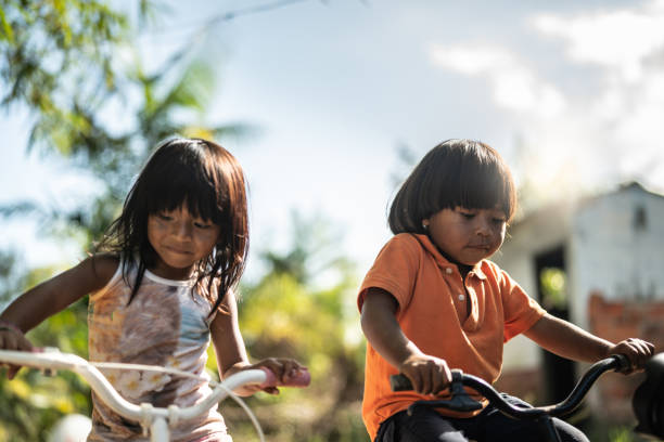 duas crianças andando de bicicleta em um lugar rural - tribal life - fotografias e filmes do acervo