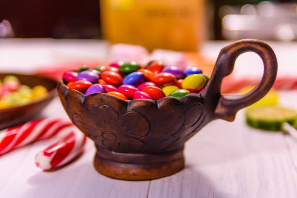 istock Ceramic bowl with colored candies, lollipops and marshmallows on a wooden table 1017510446