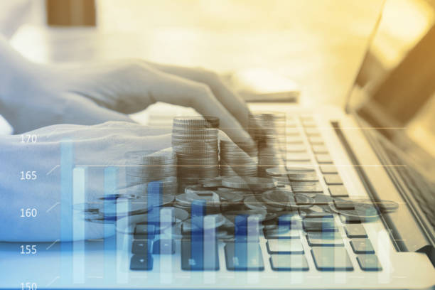 Double exposure Of women hand typing laptop and the coins in  finance and banking concept stock photo
