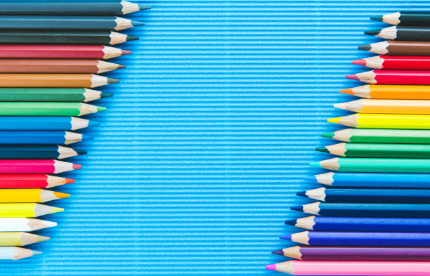 Colorful pencils on blue paper background stock photo