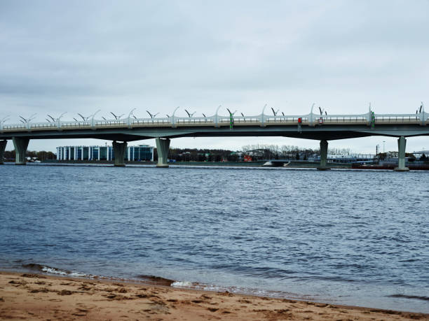 Amazing view of long bridge and modern city near waving water on gray cloudy day