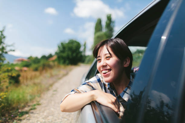 Young Japanese female traveller enjoying road trip by car A young Japanese female traveller is happily looking out of the window of a car in rural area in Turkey. august photos stock pictures, royalty-free photos & images